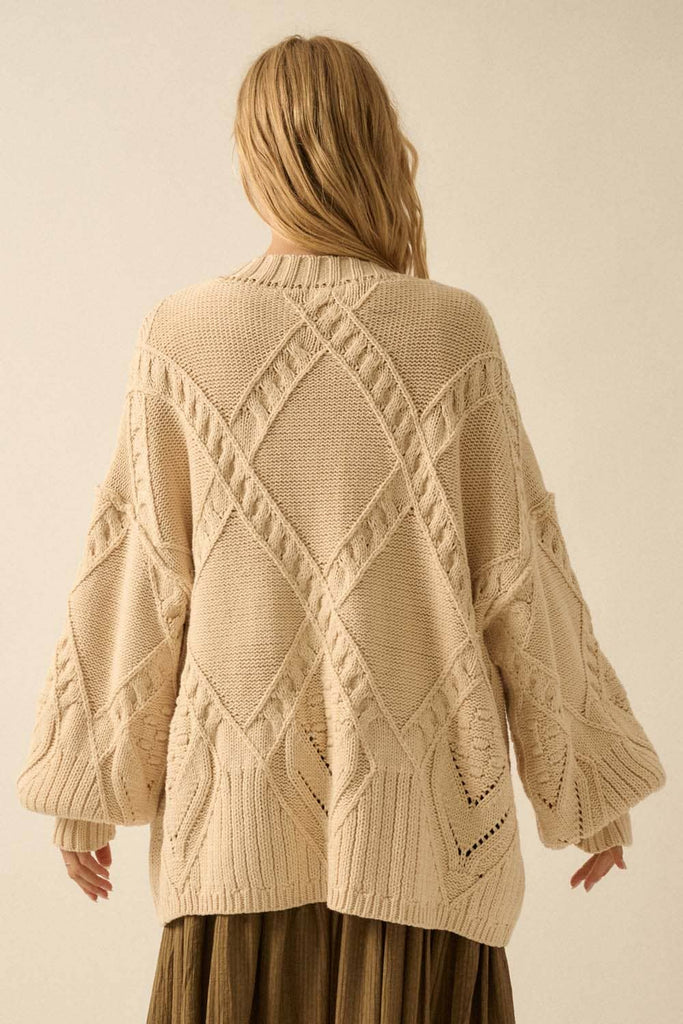 Beige knitted cardigan with geometric pattern worn by a person on a beige background