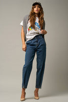  Model wearing high-waist balloon jeans with a relaxed silhouette and slightly tapered legs, paired with a casual graphic t-shirt and neutral heels.