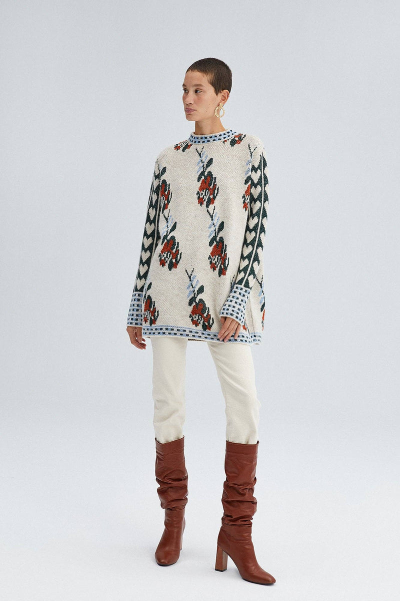 Woman wearing a Fair Isle floral knit sweater with long sleeves and mixed pattern detailing in red, green, and blue.