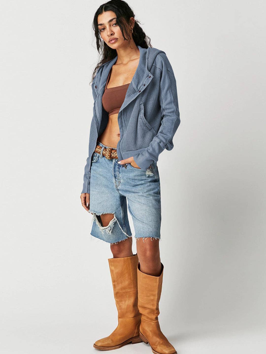 Woman wearing a Sahara Sky Hooded Jacket with a zip-up front, textured waffle knit, and button detailing in blue and brown tones.