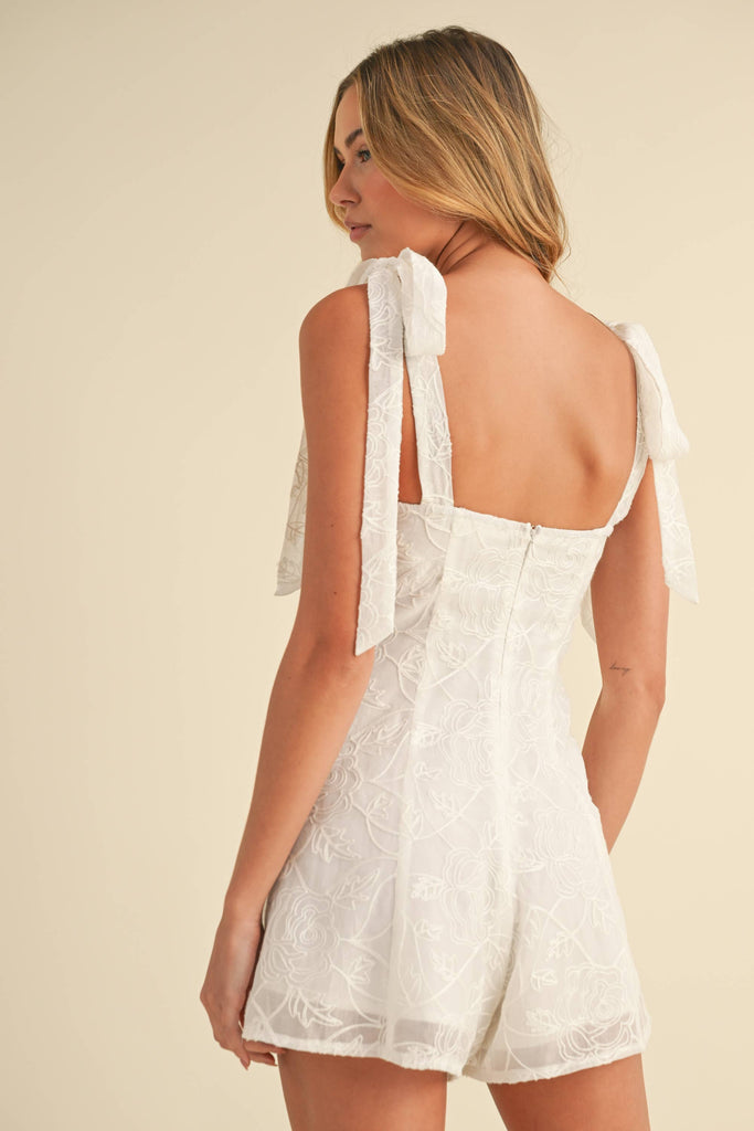 White embroidered romper with shoulder tie straps, worn by model facing front and back
