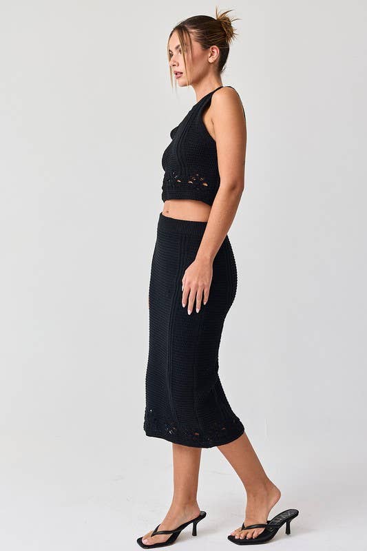 Woman wearing a black sleeveless crochet top and midi skirt set.