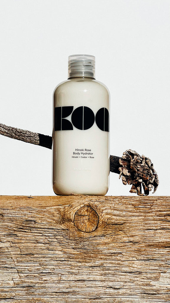 Bottle of Koa Hinoki Rose Body Hydrator, featuring a minimalist design with bold black lettering on a white background.