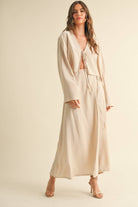 Woman wearing a beige tie-front long sleeve top and matching wrap maxi skirt, styled as a coordinated skirt set.