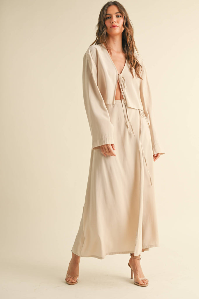Woman wearing a beige tie-front long sleeve top and matching wrap maxi skirt, styled as a coordinated skirt set.