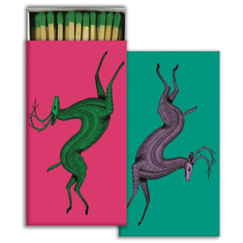 Artistic matchbox with abstract deer illustrations on vibrant pink and green backgrounds.
