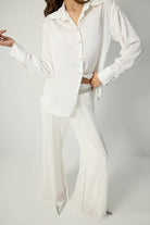White pleated chiffon flared trousers with high waist and flowy wide legs.