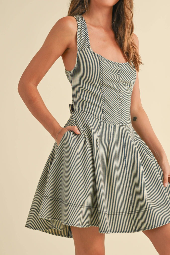 Woman wearing a sleeveless striped mini dress with criss-cross back straps and a large bow tie at the waist.