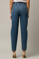 Model wearing high-waist balloon jeans with a relaxed silhouette and slightly tapered legs, paired with a casual graphic t-shirt and neutral heels.