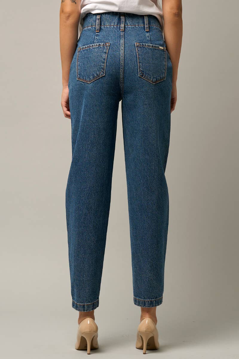  Model wearing high-waist balloon jeans with a relaxed silhouette and slightly tapered legs, paired with a casual graphic t-shirt and neutral heels.
