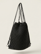 Black woven drawstring bag on a light beige background