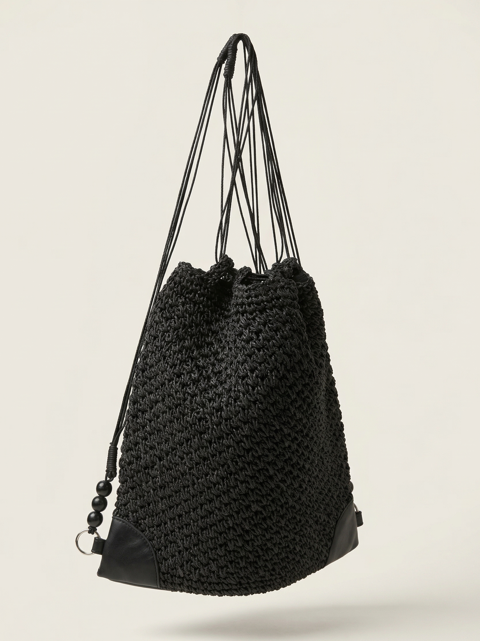 Black woven drawstring bag on a light beige background
