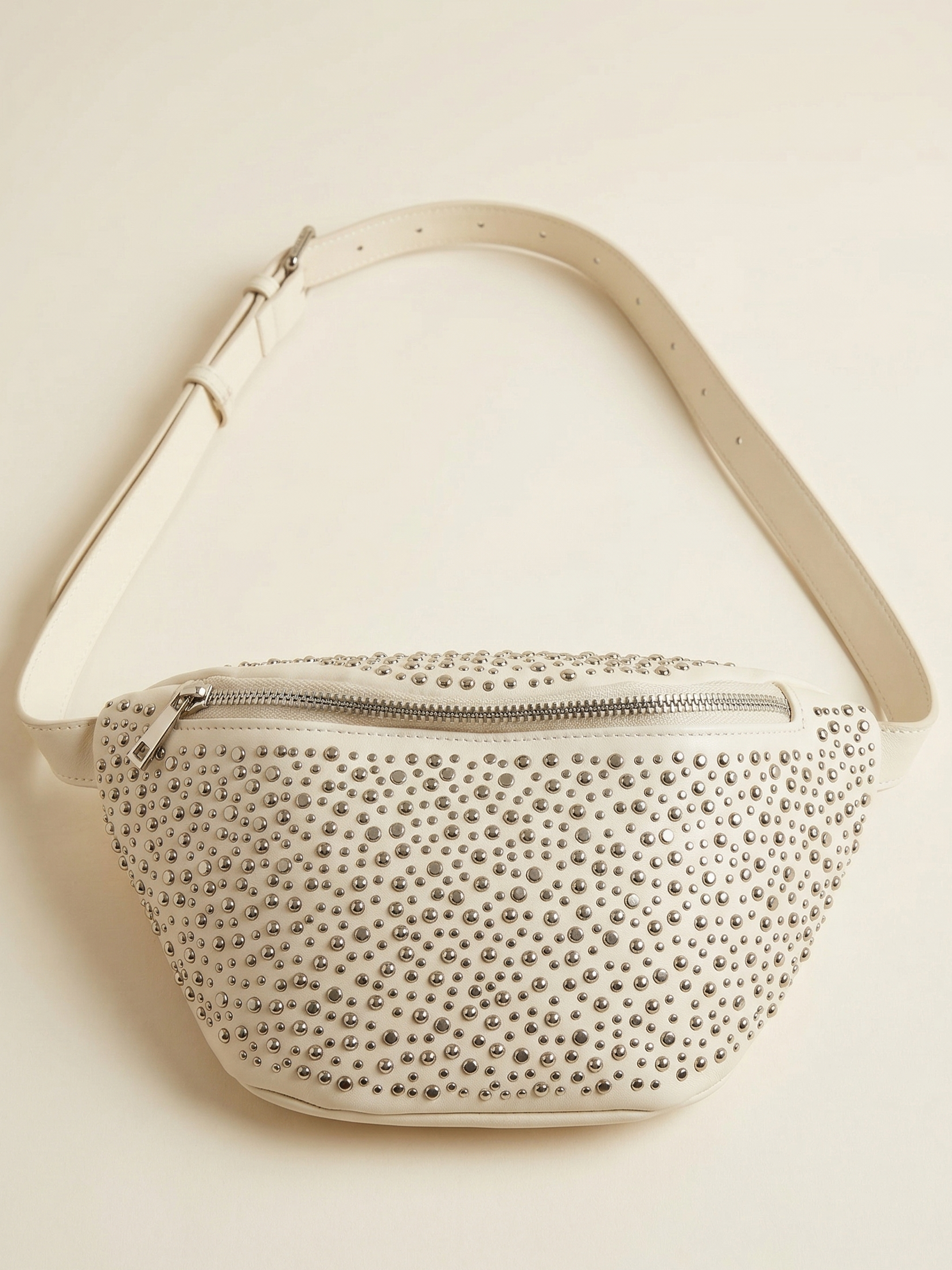 Studded handbag with beige strap on a light beige background