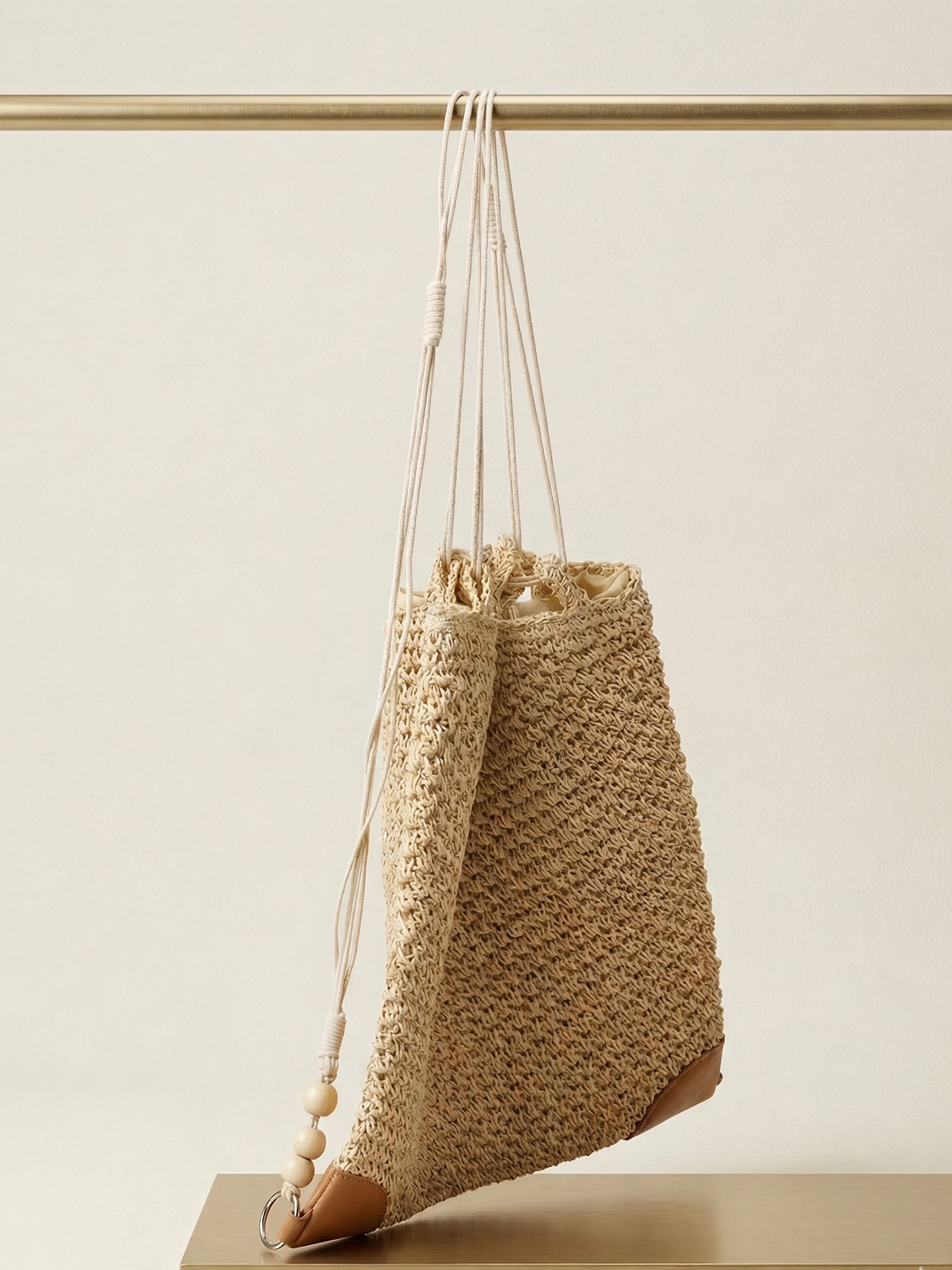 Woven bag with drawstring and tassel on a neutral background