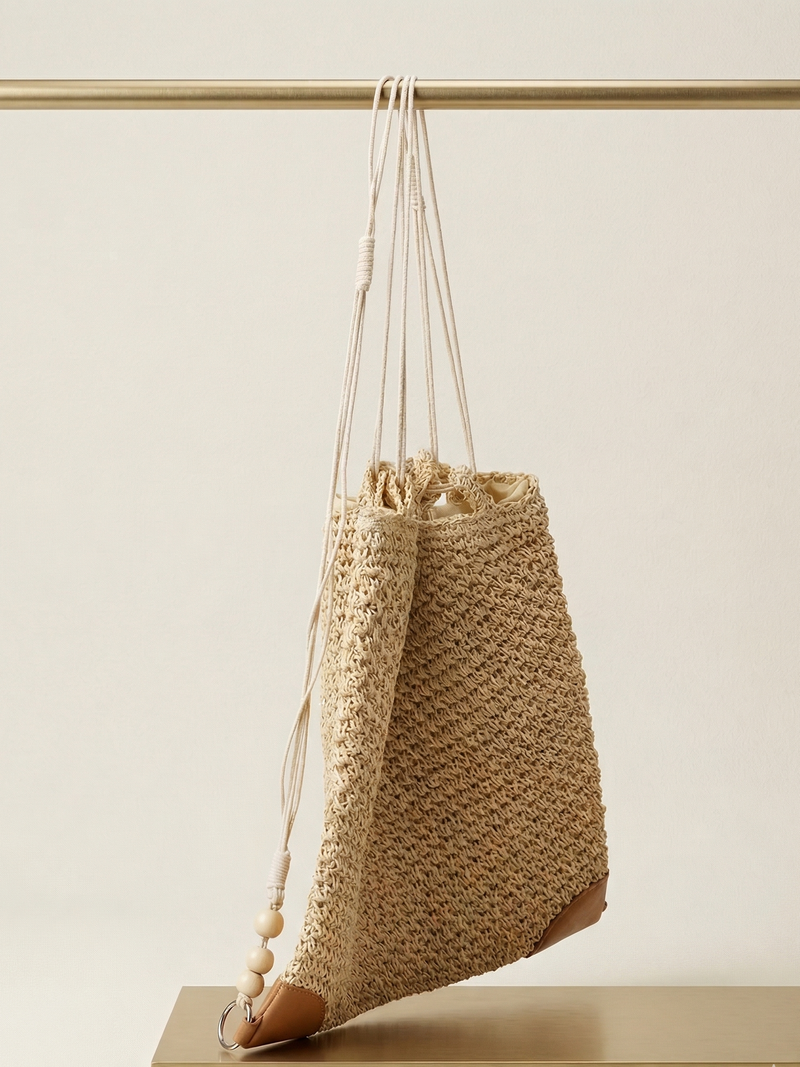 Woven bag with drawstring and tassel on a neutral background