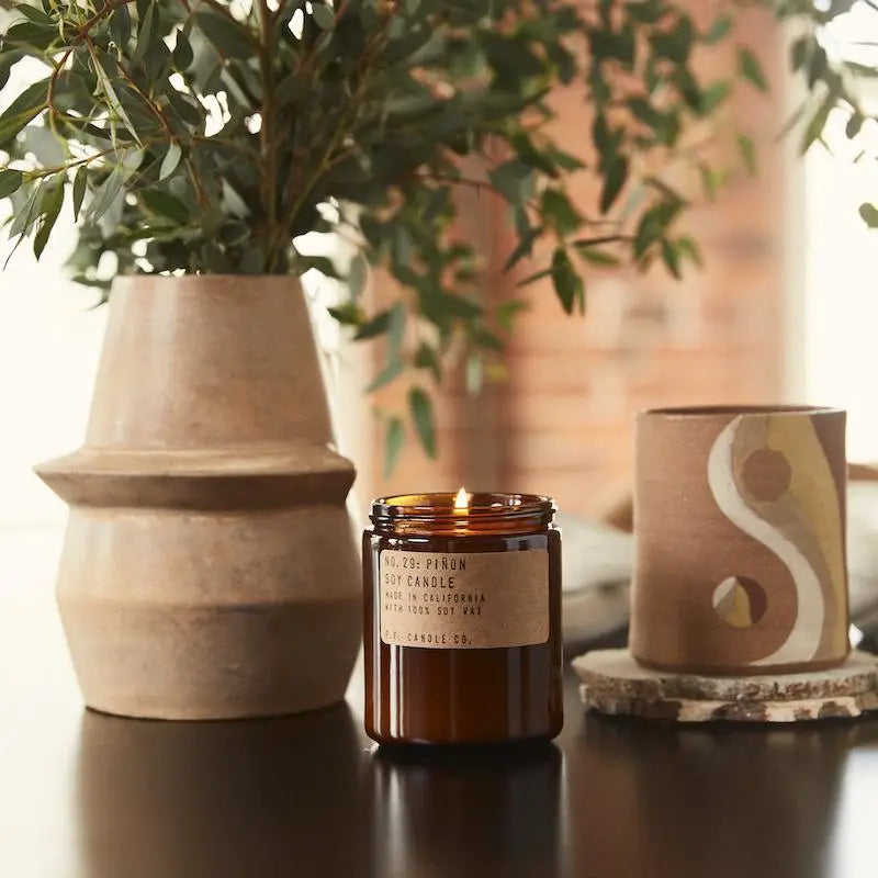 Piñon Soy Candle in recyclable packaging, releasing a warm, earthy piñon pine scent.