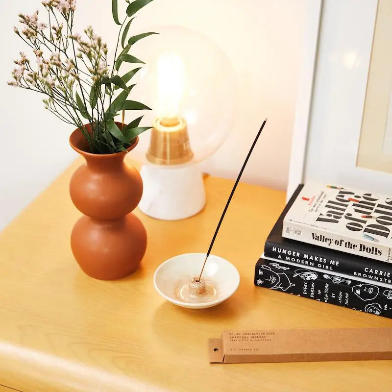 A pack of Sandalwood Rose Incense sticks, gracefully aligned, with rose petals.