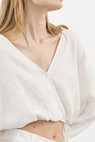 Siena Top displayed on a hanger, showcasing its wide sleeves and the unique V-shaped front drape with a hidden optional closure.