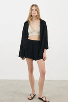 A woman wearing the Sundown Top, showcasing its relaxed fit, short sleeves, and flattering neckline, a versatile and stylish option for any occasion.
