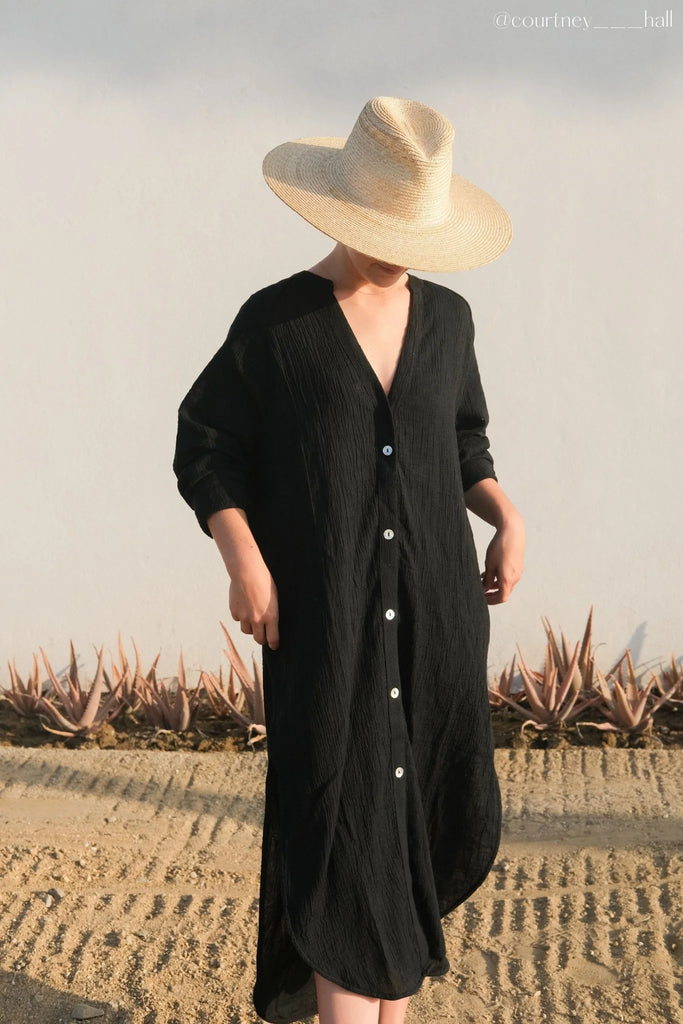 A woman wearing the Terra Shirt Dress, showcasing its relaxed silhouette, button-down front, and waist tie, epitomizing casual comfort and style.