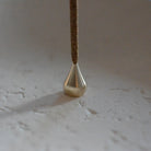 Elegant Brass Water Drop Incense Holder placed on a neutral backdrop, casting a warm glow, ideal for holding incense in style.