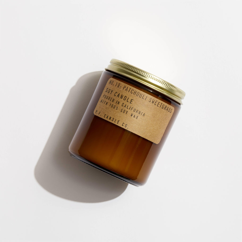 Patchouli Sweetgrass Soy Candle in a simple glass jar, with a label showcasing the rich, earthy blend of patchouli and sweetgrass.