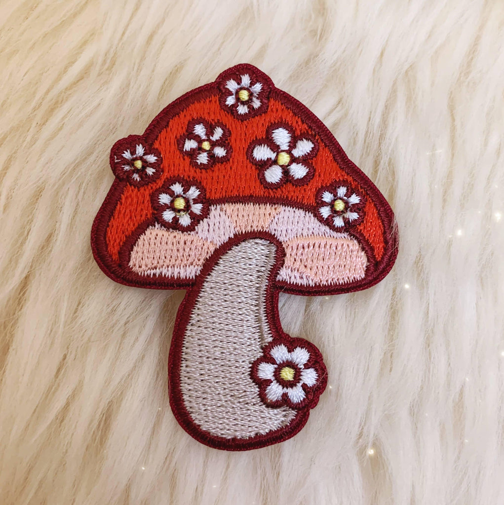 Embroidered patch showcasing a mushroom surrounded by delicate daisies.