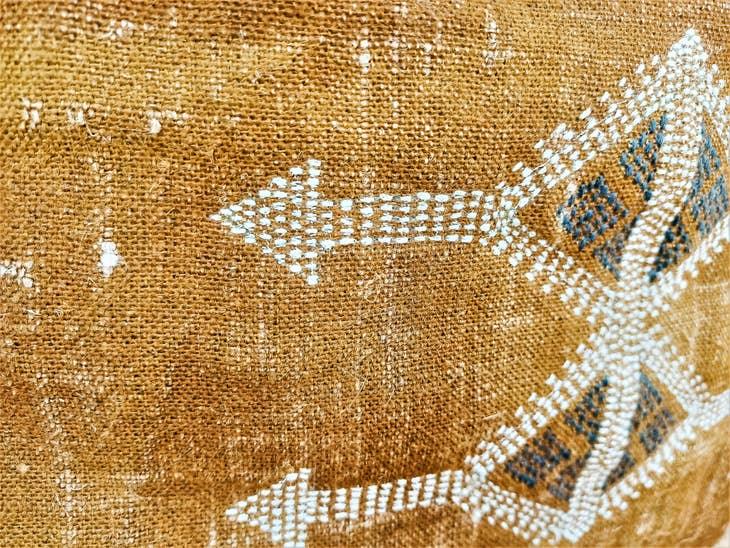 Image of the 'Moroccan Rug Design Embroidered Pillow Cover', highlighting the hand-embroidered motifs, the hand-painted color, and the handmade cotton yarn tassels.