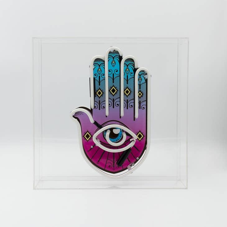 Yellow, pink, and white Neon Hamsa Hand Light encased in a glossy acrylic box with printed graphics by FORMA.