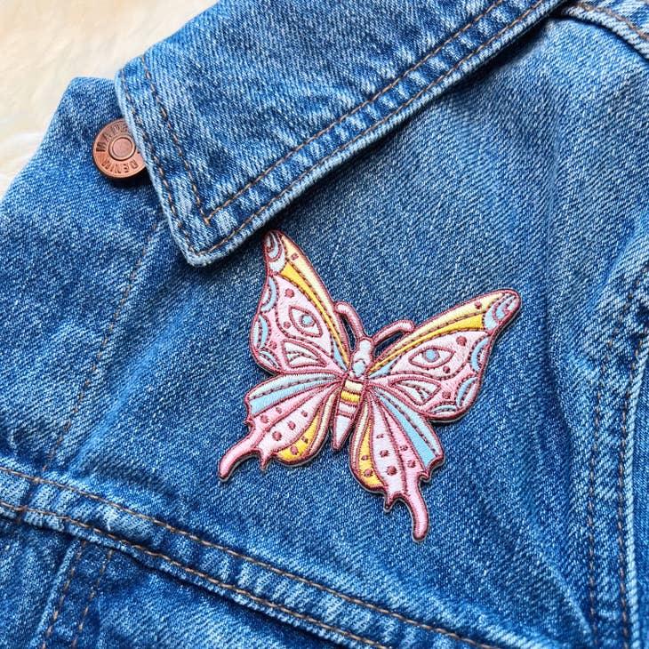 Embroidered patch of a luminous butterfly with intricate, mystical designs.