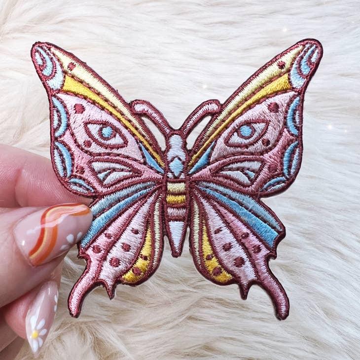 Embroidered patch of a luminous butterfly with intricate, mystical designs.