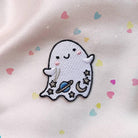 Iridescent glitter ghost patch with cosmic details - planet, moon, and stars, bordered by a shimmering gold trim.