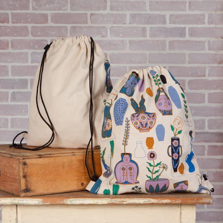 Still Life Cinch Backpack - Modern drawstring bag featuring a contrasting palette of blue, mauve, and green on a white background.