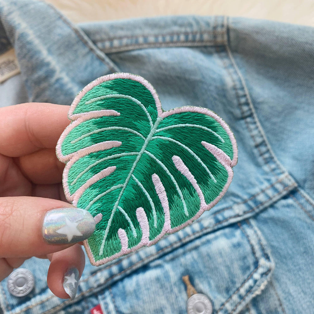 Detailed embroidered patch showcasing the iconic Monstera leaf's split design.