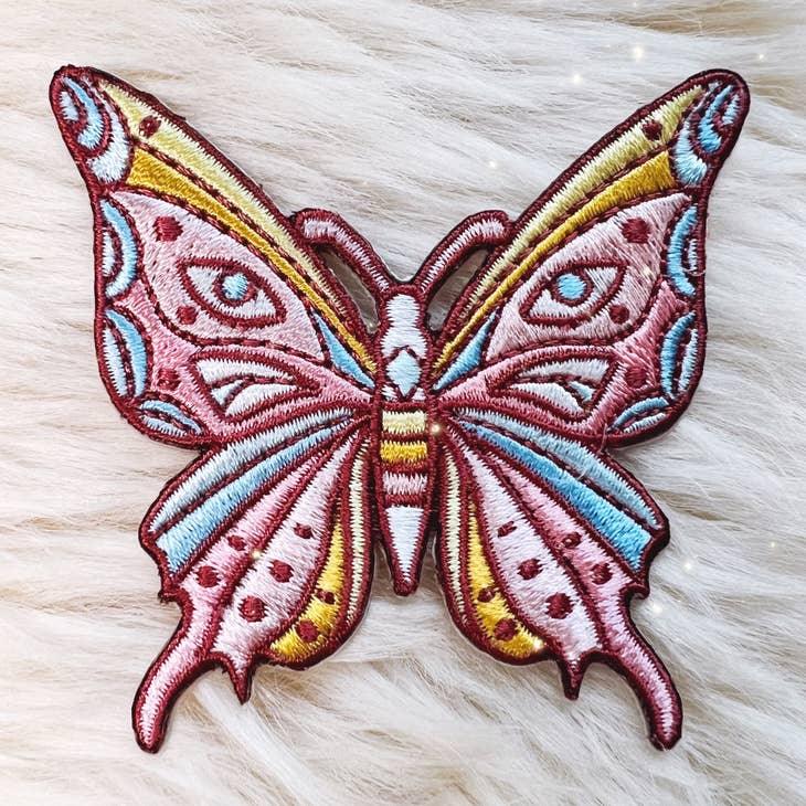 Embroidered patch of a luminous butterfly with intricate, mystical designs.