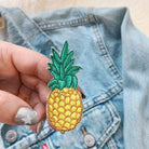 Golden embroidered pineapple patch with detailed green leaves.