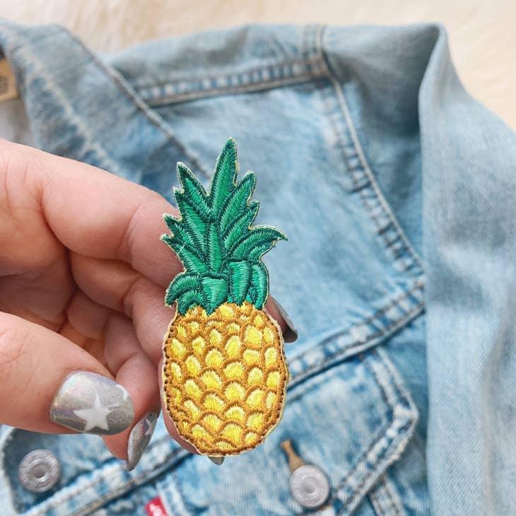 Golden embroidered pineapple patch with detailed green leaves.
