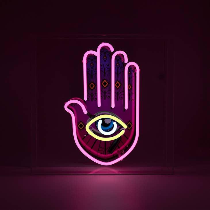 Yellow, pink, and white Neon Hamsa Hand Light encased in a glossy acrylic box with printed graphics by FORMA.