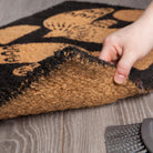 Myth Doormat - Biodegradable coir doormat with soaring dove design against a rustic black backdrop.