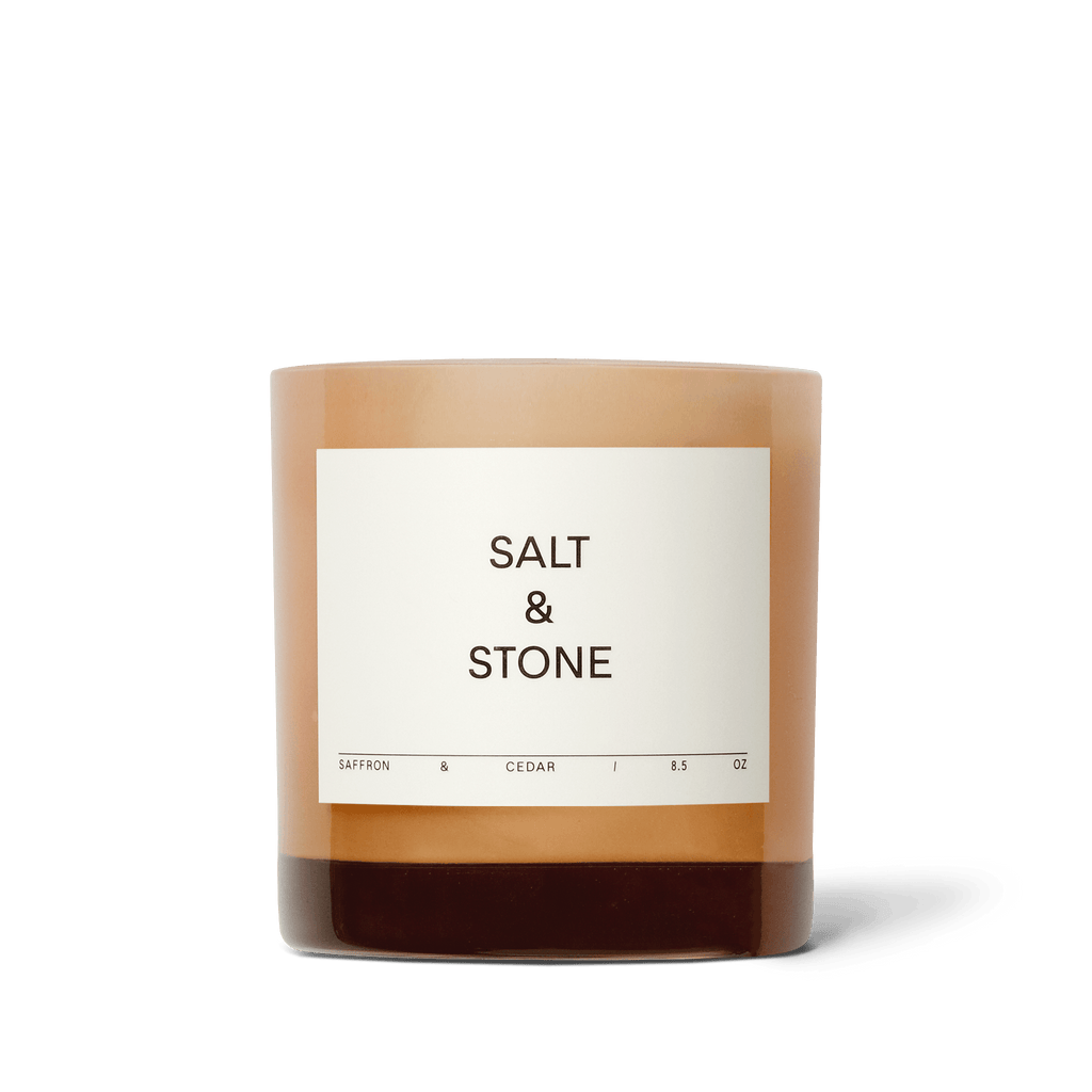 Salt & Stone Candle in Saffron & Cedar, glowing warmly, adding a touch of elegance to the space.