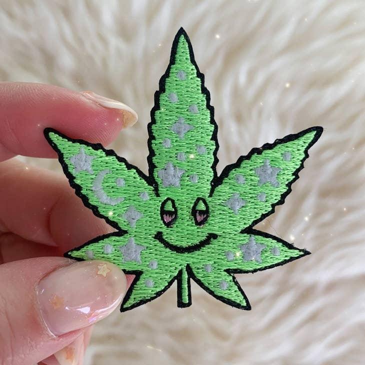 Cosmic Stoner Weed Patch, featuring a weed leaf intertwined with vibrant cosmic designs and celestial symbols.