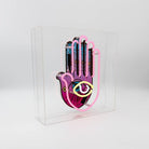 Yellow, pink, and white Neon Hamsa Hand Light encased in a glossy acrylic box with printed graphics by FORMA.