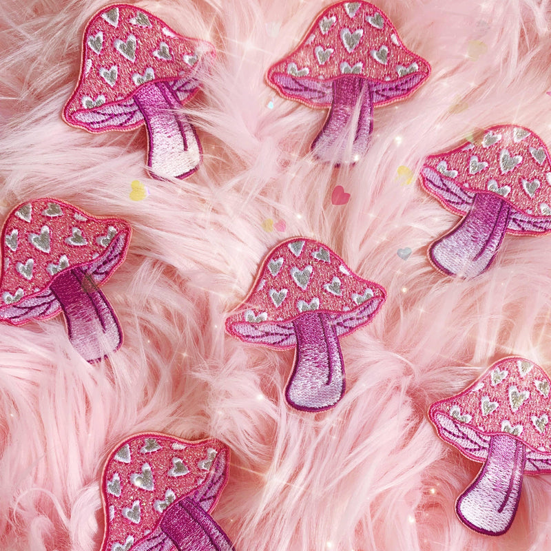 Embroidered patch depicting a mushroom shaped as a heart in vibrant colors.