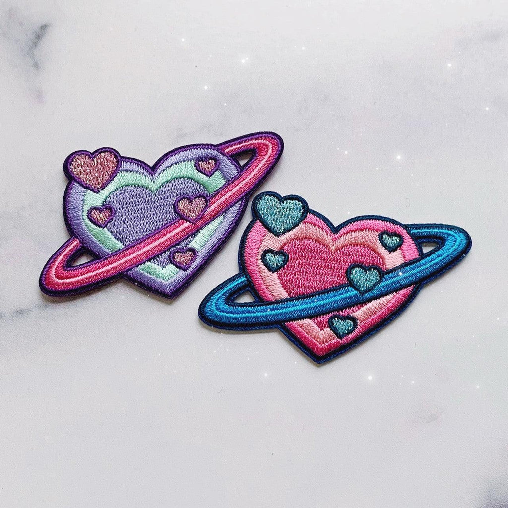 Embroidered patch showcasing a planet in the form of a heart with intricate details.