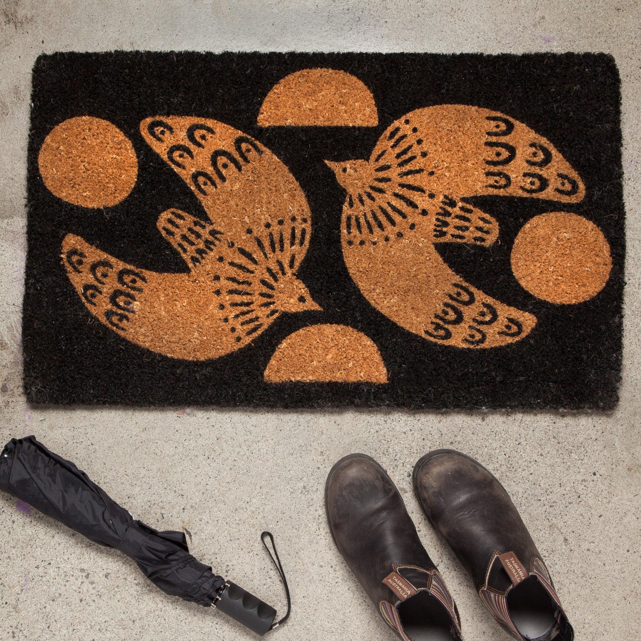 Myth Doormat - Biodegradable coir doormat with soaring dove design against a rustic black backdrop.