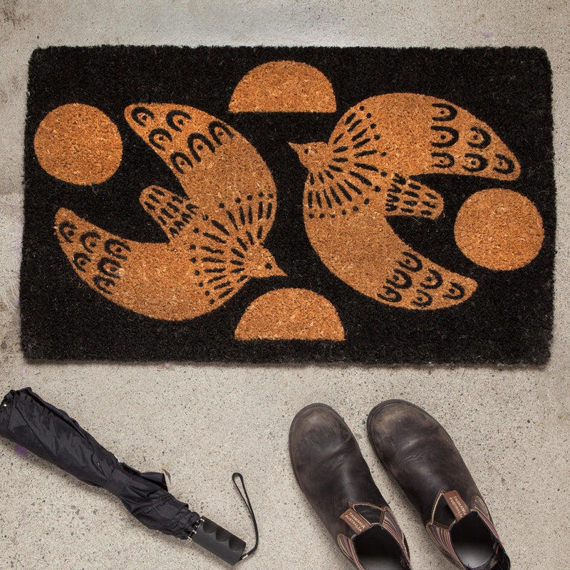 Myth Doormat - Biodegradable coir doormat with soaring dove design against a rustic black backdrop.